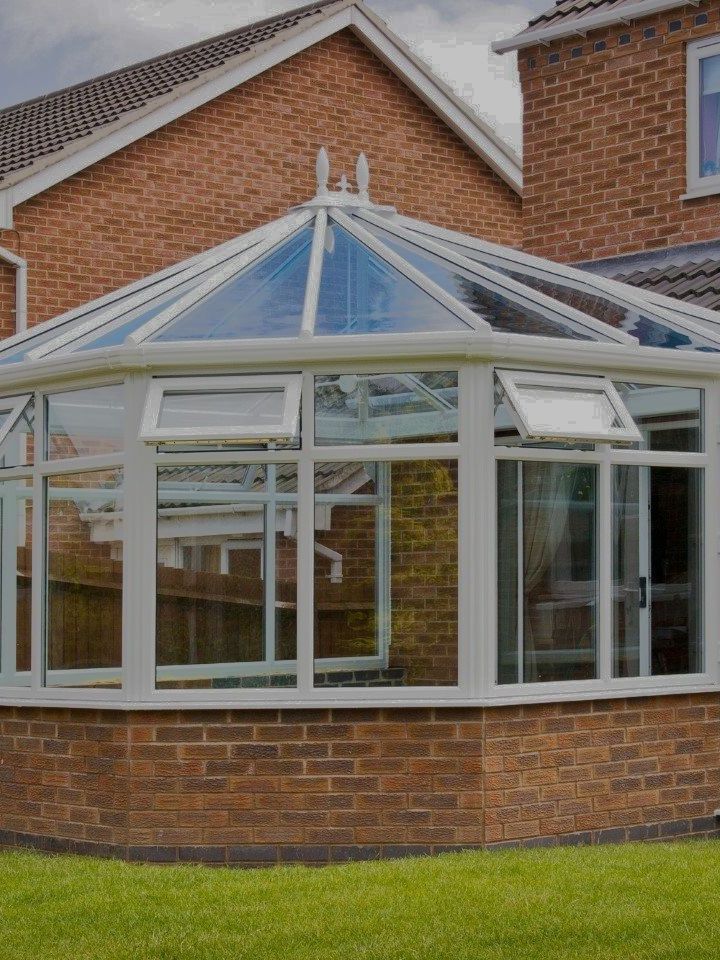 a brick house with a glass conservatory in front of it