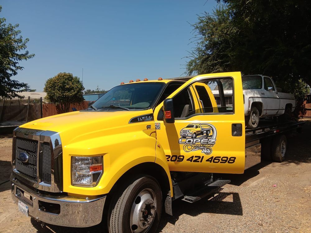 A yellow Ford flatbed tow truck with the name 