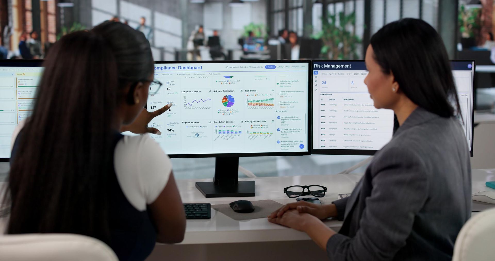 Two people reviewing data on dual monitors in an office workspace