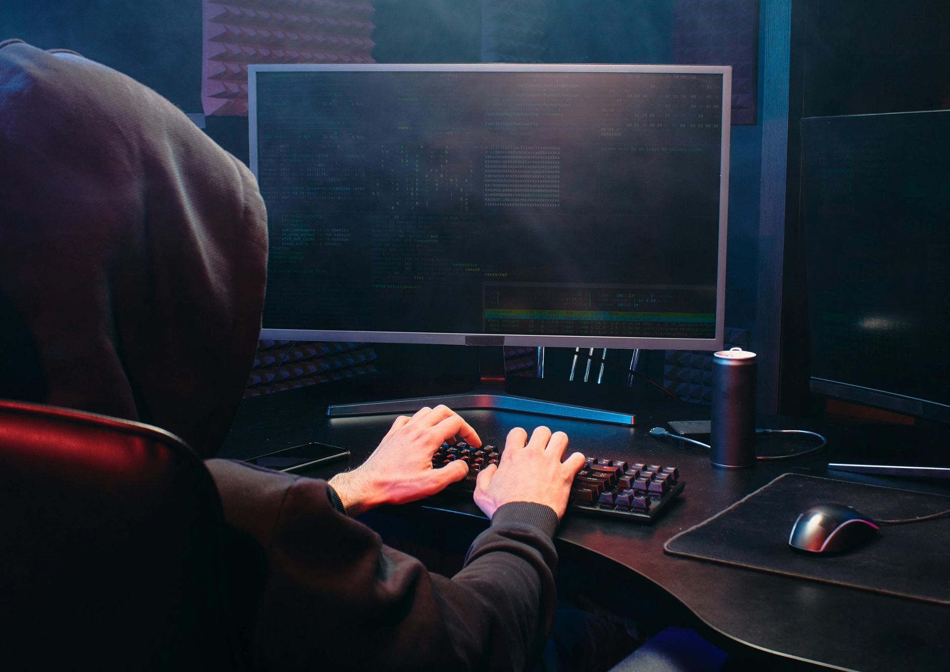 Person typing at a desktop computer in a dark, neon-lit room