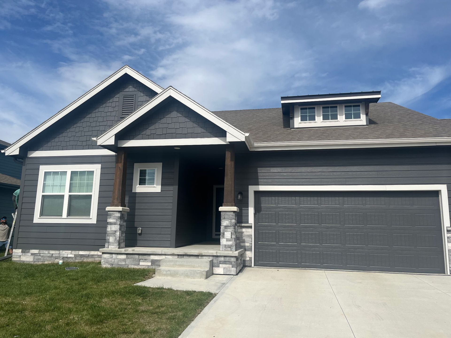 A gray house with a garage door and a porch