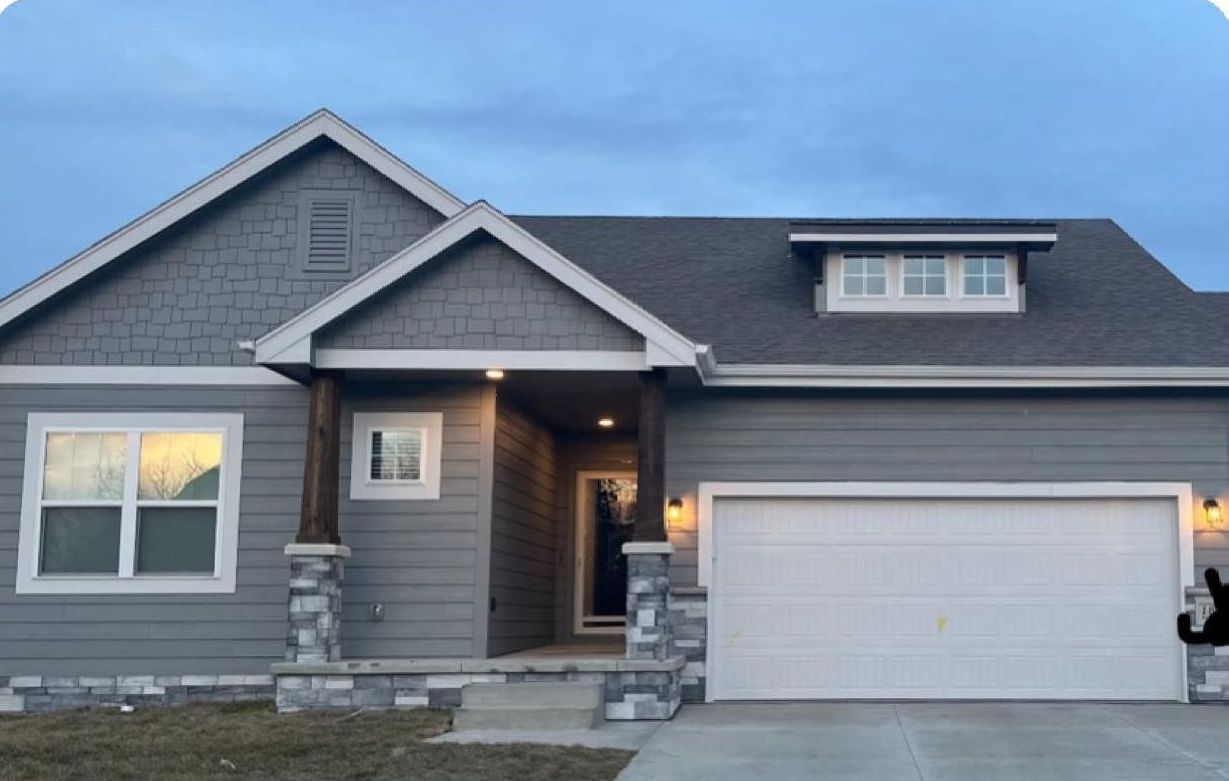 A gray house with a white garage door and a gray roof