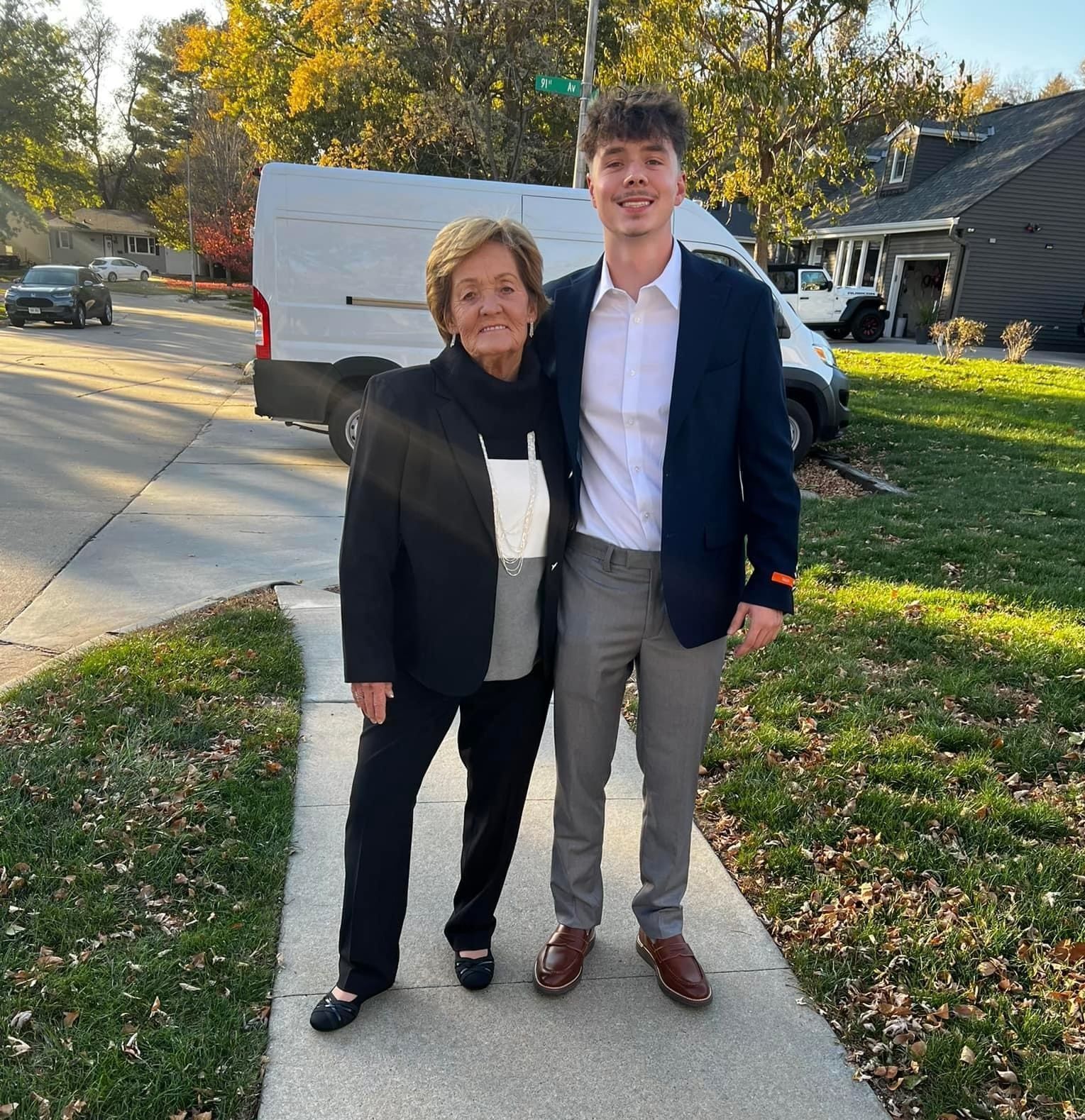 A man and a woman are posing for a picture on a sidewalk