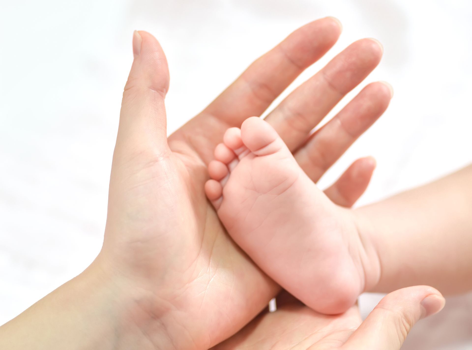 At a pregnancy care center, a mother gently cradles a newborn's tiny foot after birth. 