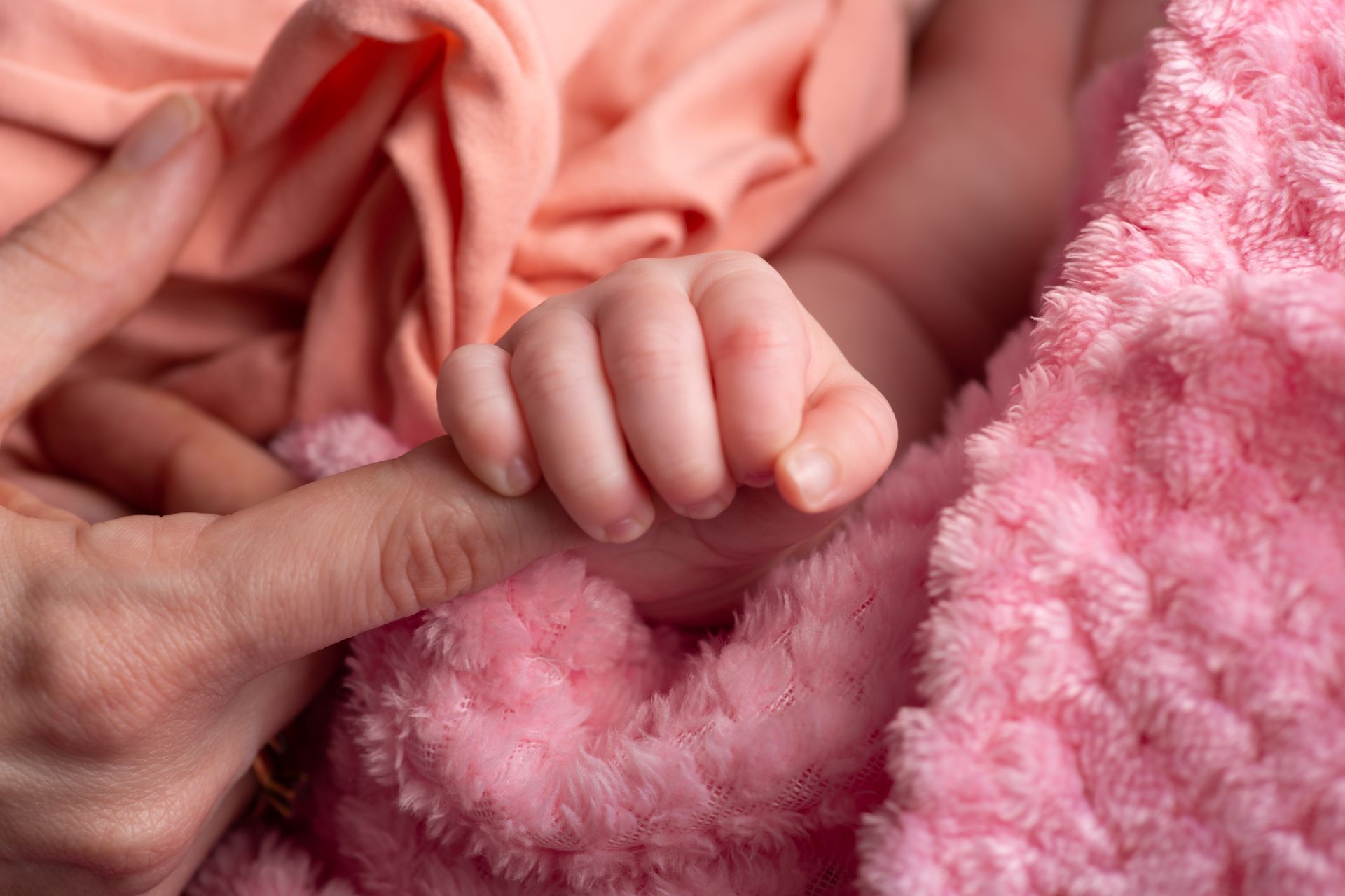 Close-up of a newborn baby’s hand gently gripping a mother’s finger, highlighting early bonding and connection.
