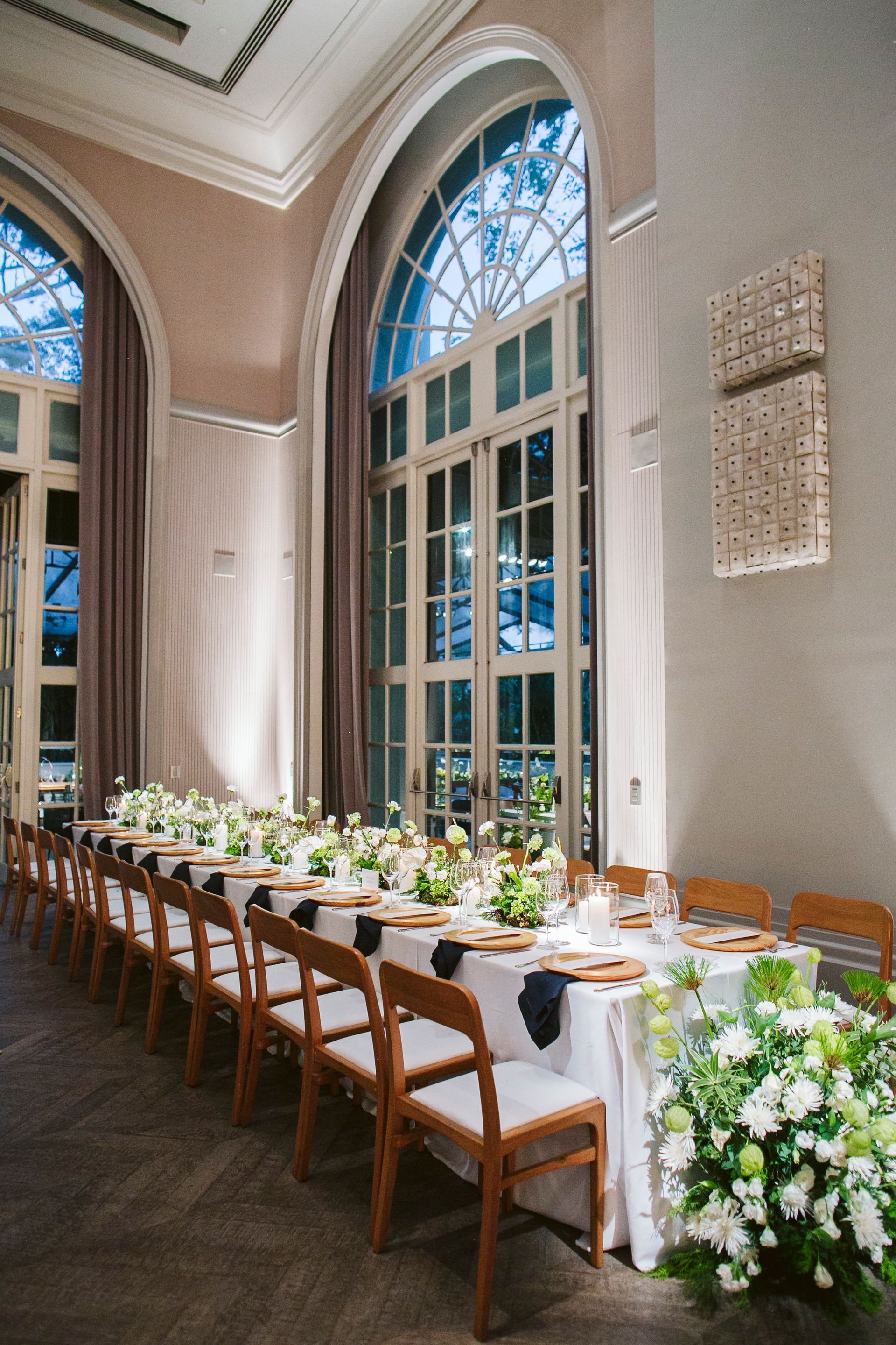 Uma mesa longa com muitas cadeiras em uma sala com muitas janelas.