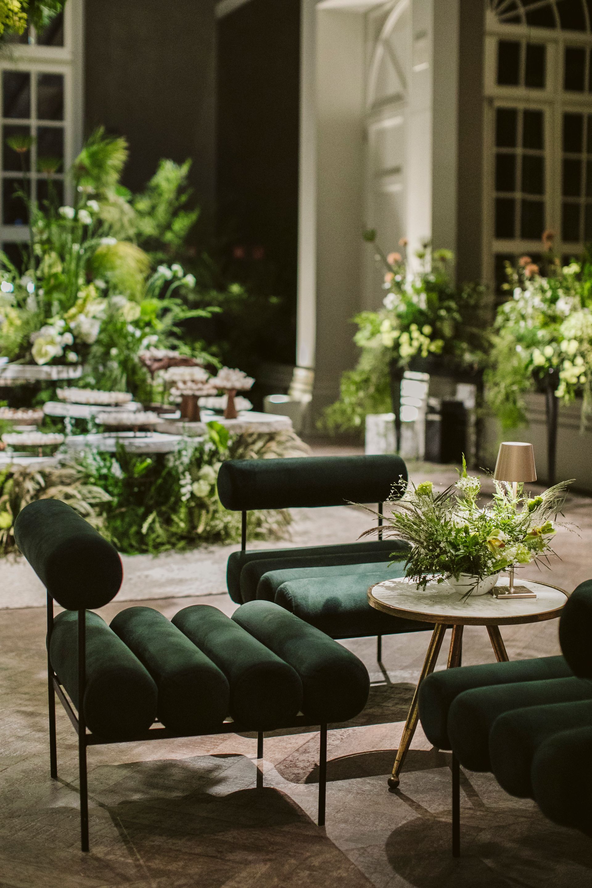 Uma sala com cadeiras verdes e uma mesa com flores.