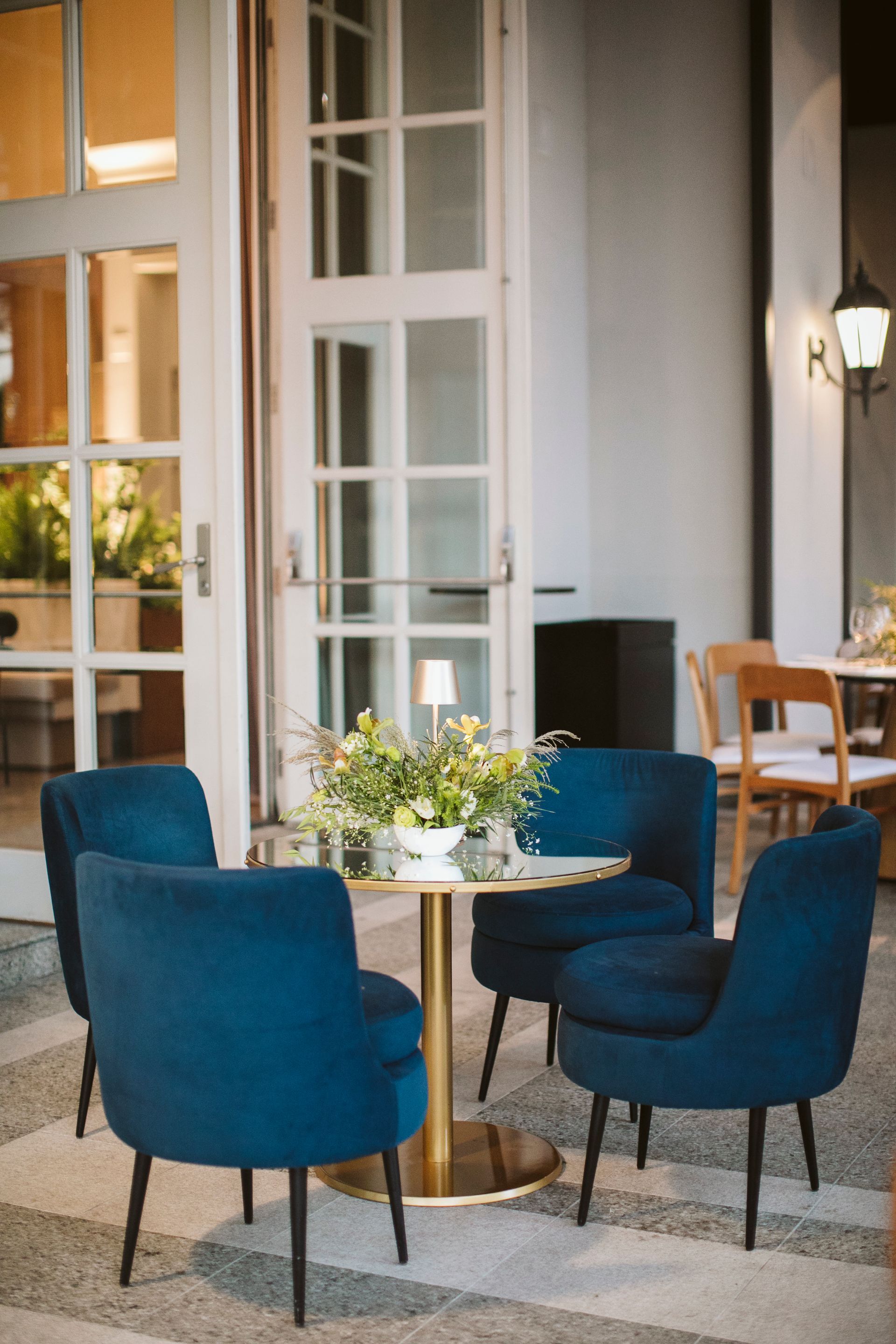 Uma sala com cadeiras azuis e uma mesa com um vaso de flores.