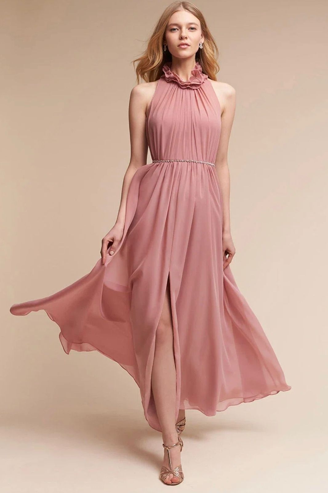 Uma mulher está usando um vestido longo rosa com uma fenda alta.