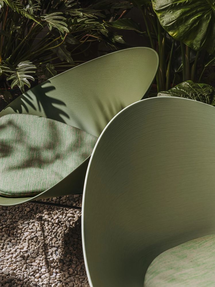 Duas cadeiras verdes estão sentadas uma ao lado da outra sobre um tapete.