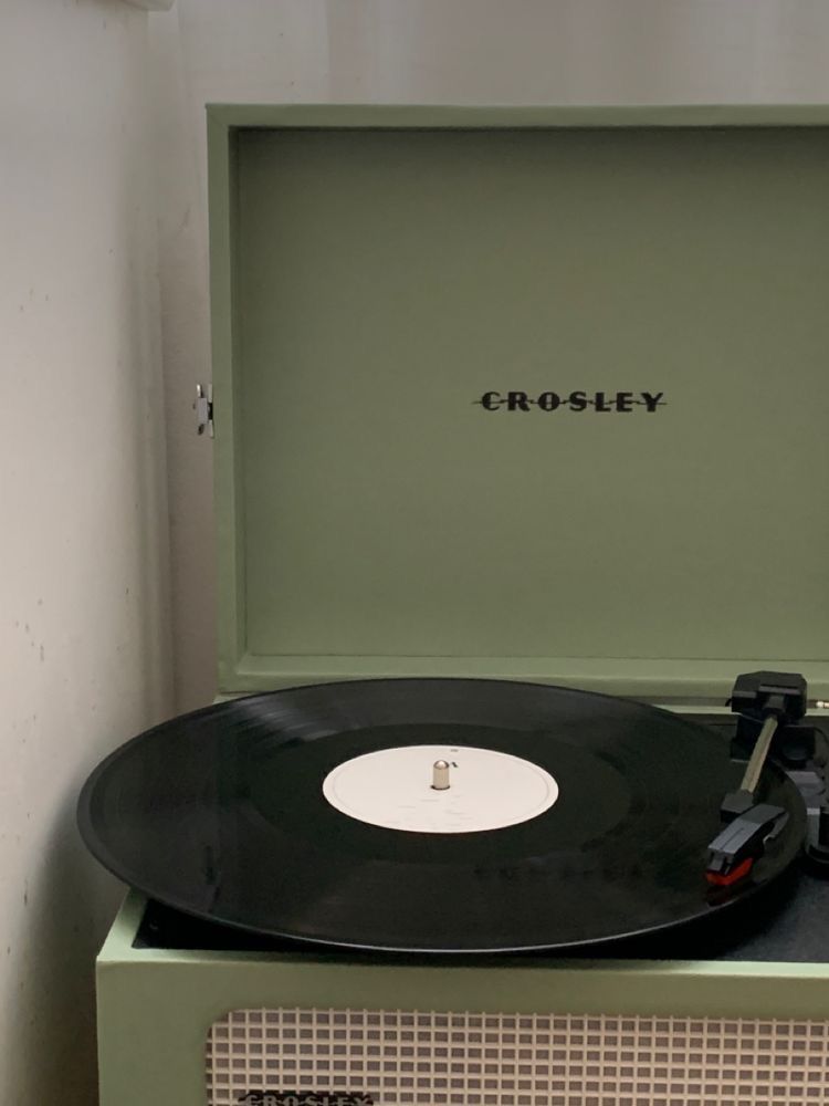 Um toca-discos está tocando um disco em uma caixa verde.