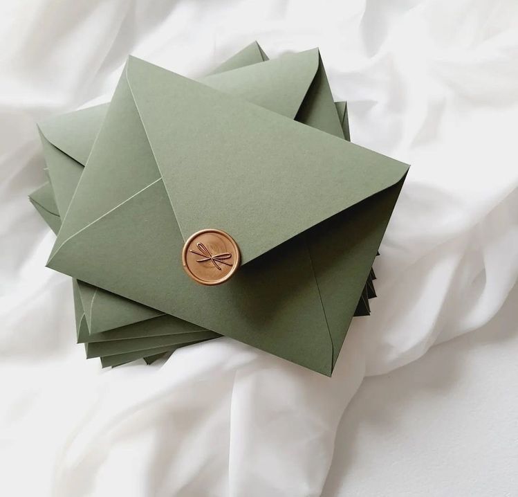 Uma pilha de envelopes verdes com um selo de cera dourada