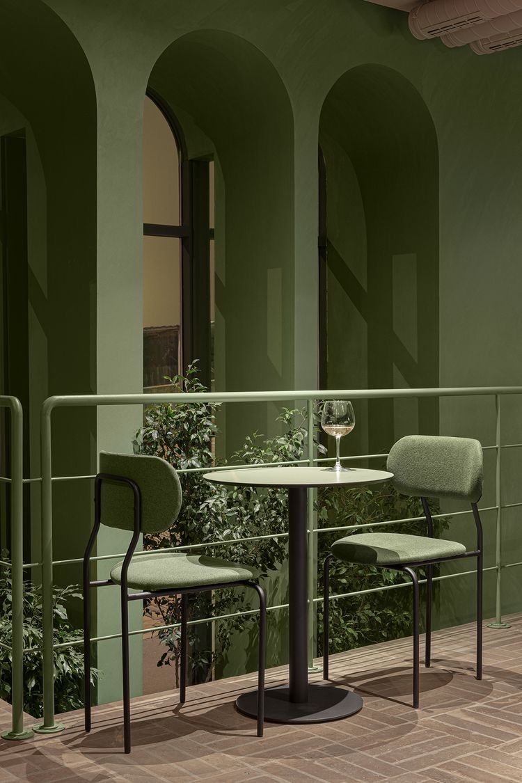 Uma varanda com duas cadeiras e uma mesa com uma taça de vinho.