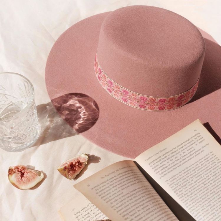 Um chapéu rosa está em cima de um livro aberto