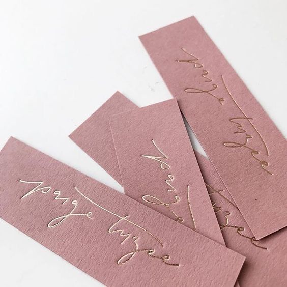 Um close de três marcadores rosa com letras douradas neles