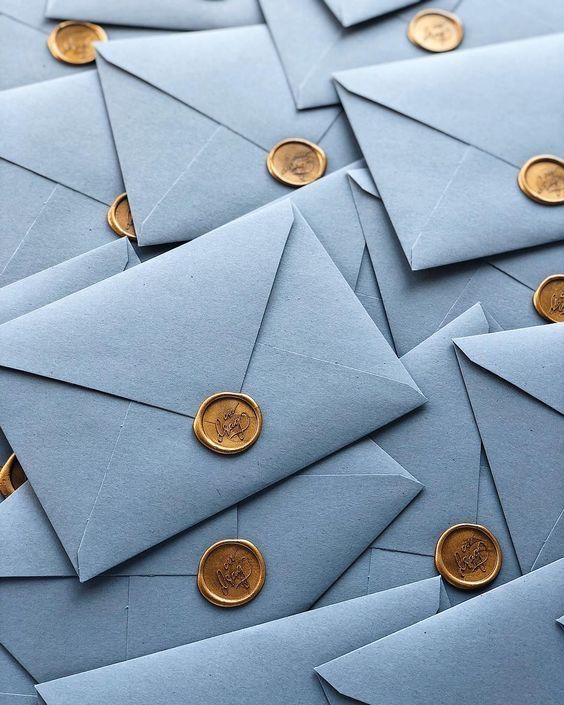 Uma pilha de envelopes azuis com selos de cera dourada