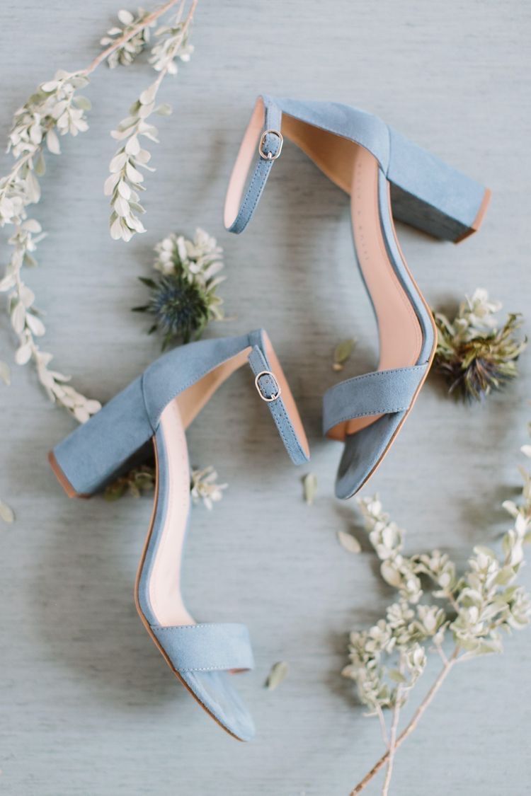 Um par de saltos azuis claros em cima de uma mesa ao lado de flores.