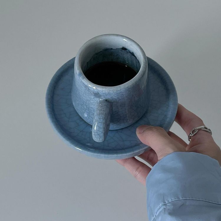 Uma pessoa está segurando uma xícara de café em um pires.