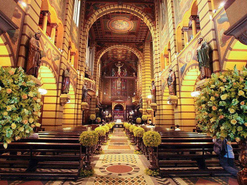 O interior de uma igreja decorada com flores e bancos.