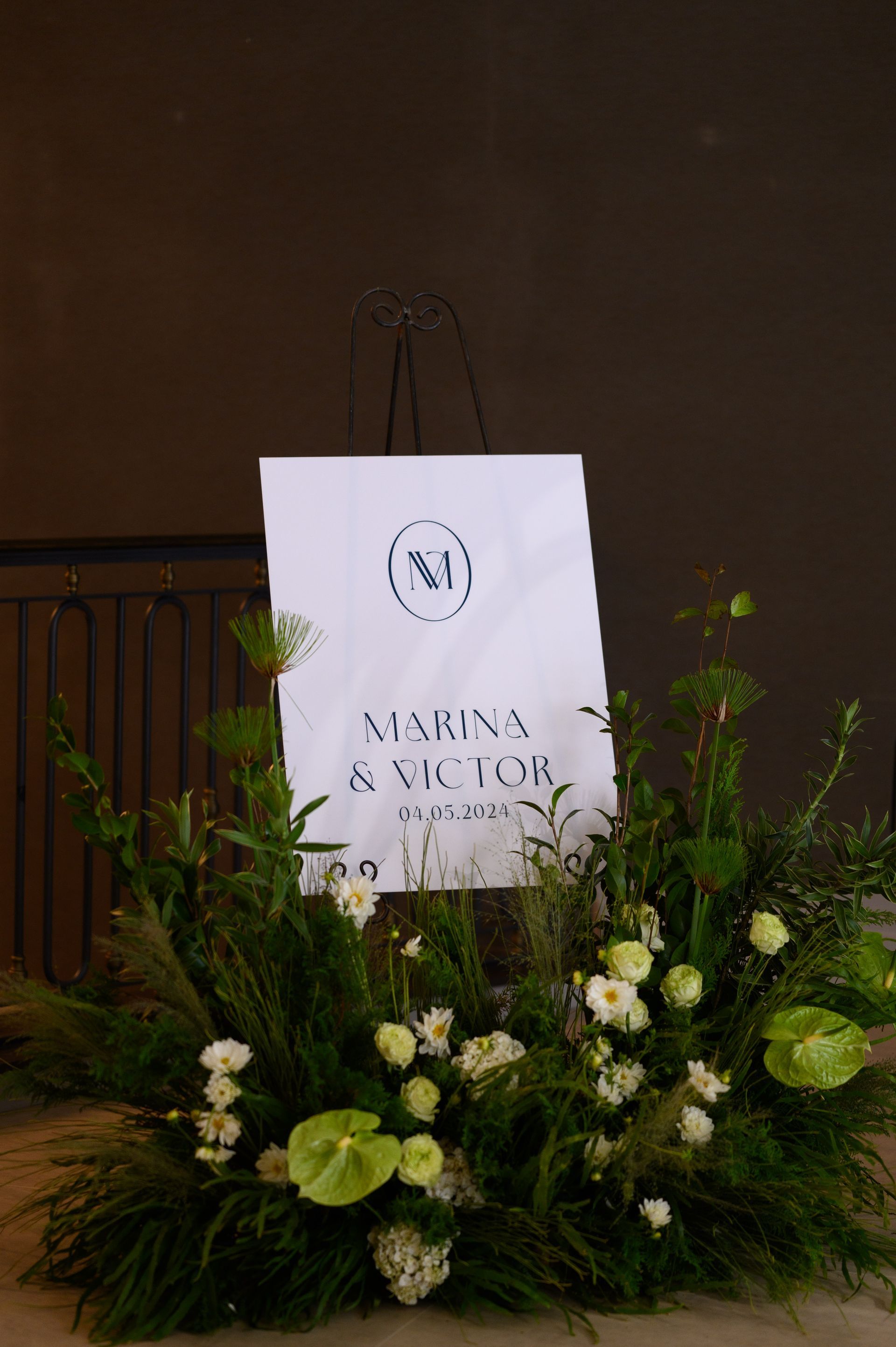 Uma placa branca cercada por vegetação e flores.