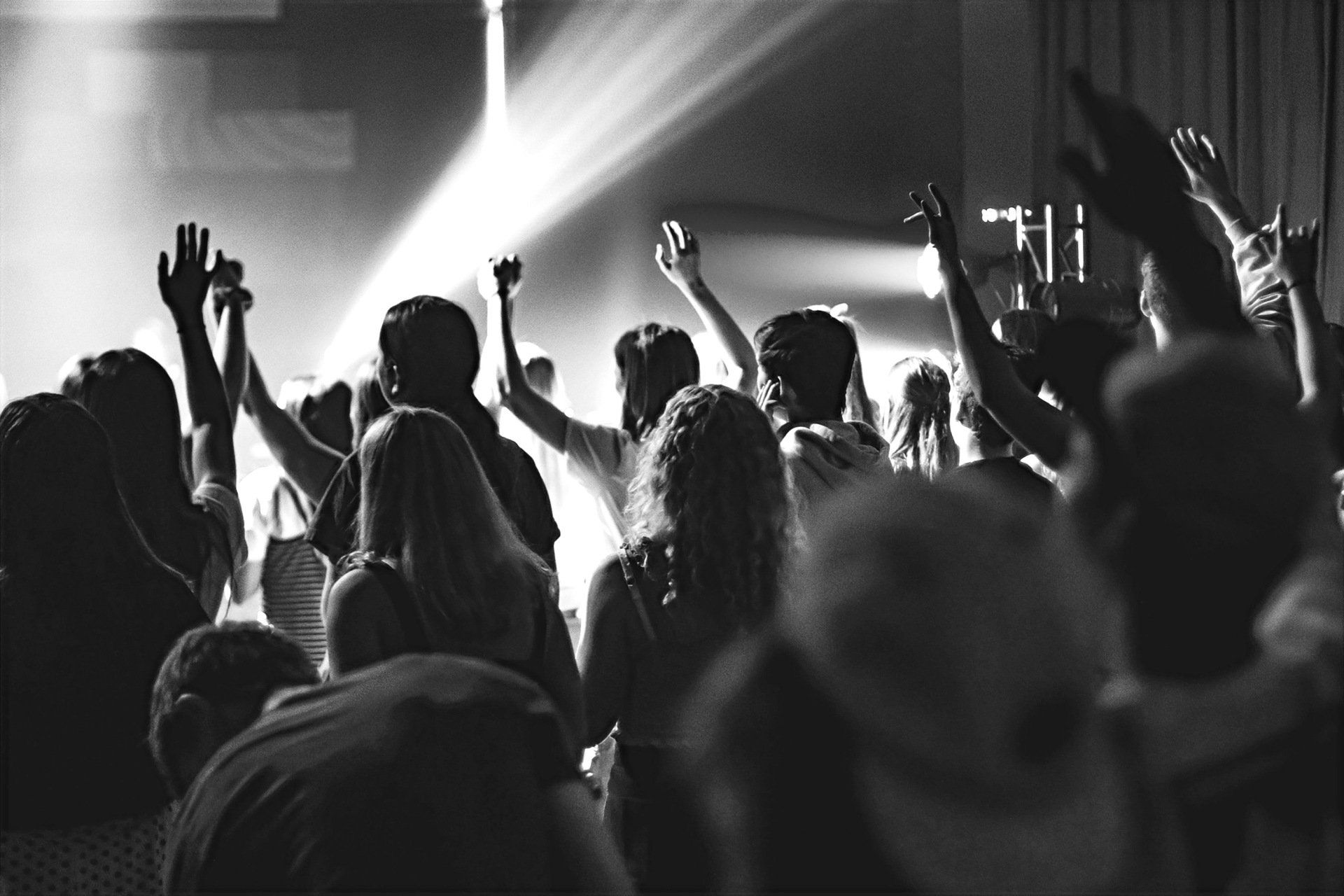 Uma multidão de pessoas levanta as mãos no ar em um show.