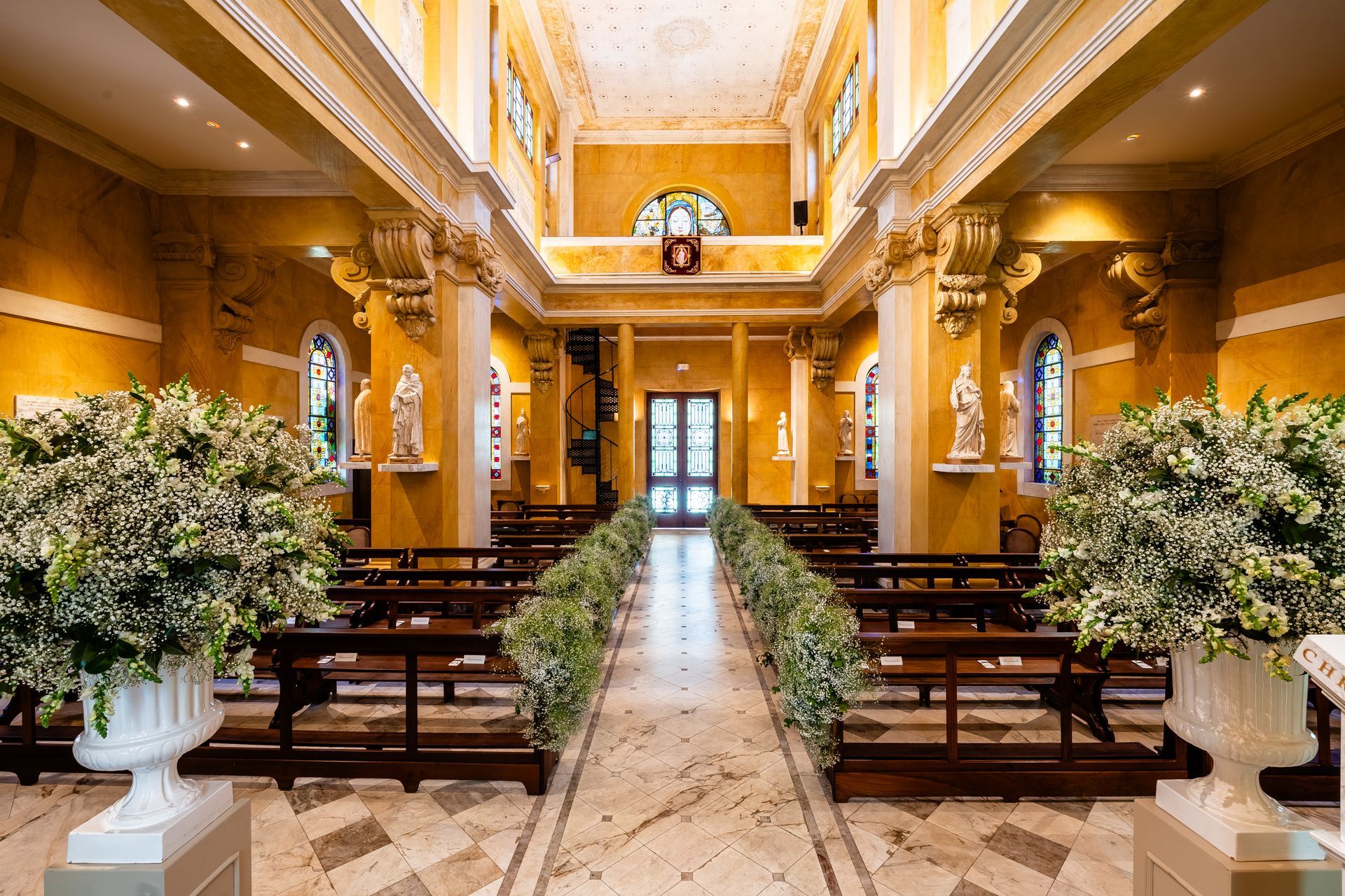 O interior de uma igreja decorada para um casamento com flores nos bancos.