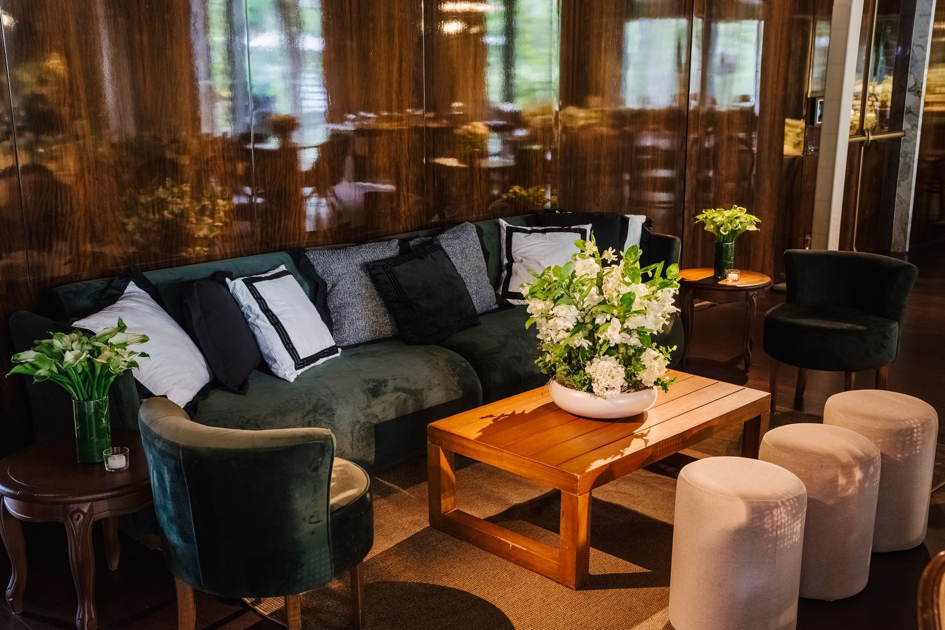 Uma sala de estar com um sofá, cadeiras, pufes e uma mesa de centro.