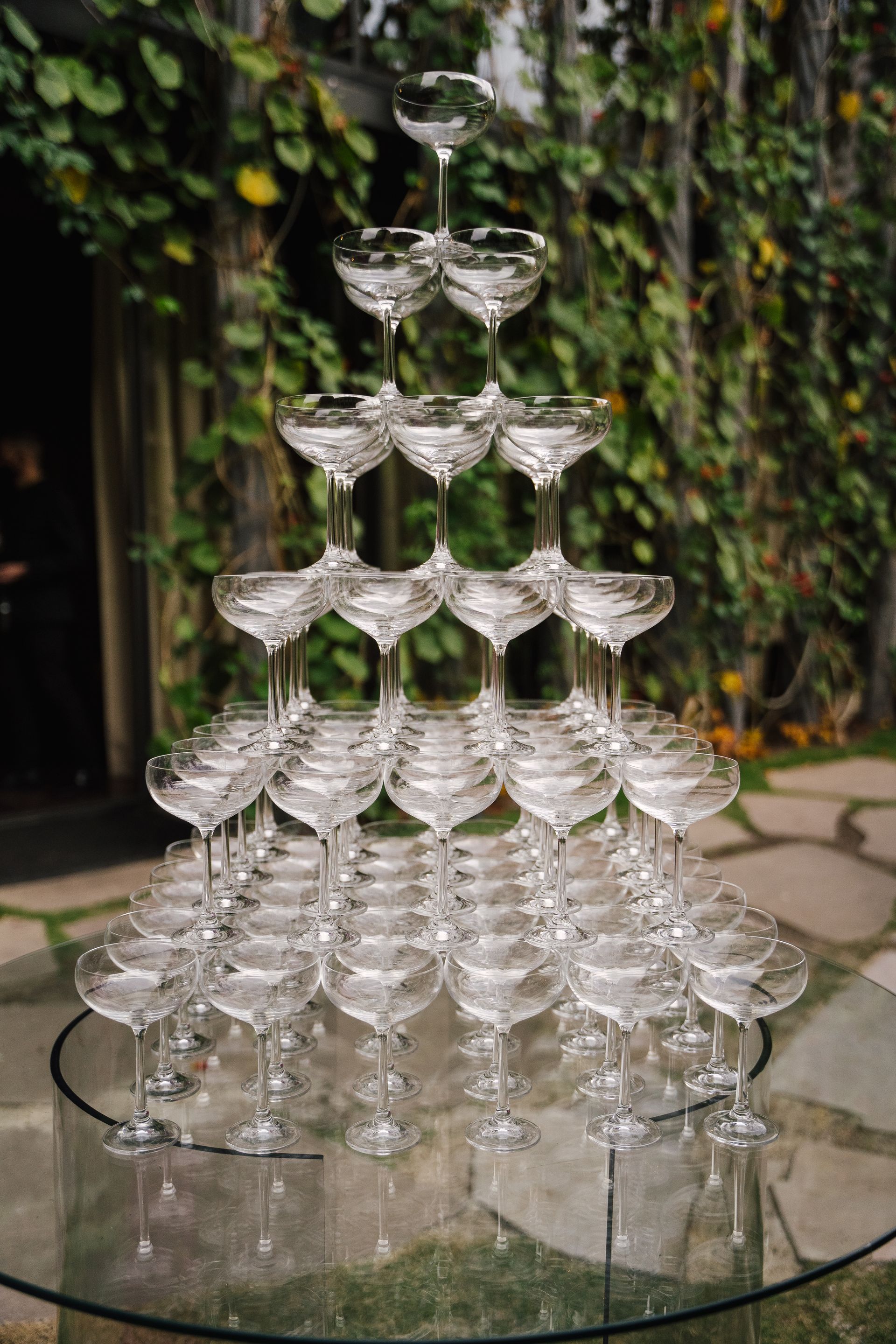 Uma pirâmide de taças de champanhe sobre uma mesa de vidro.