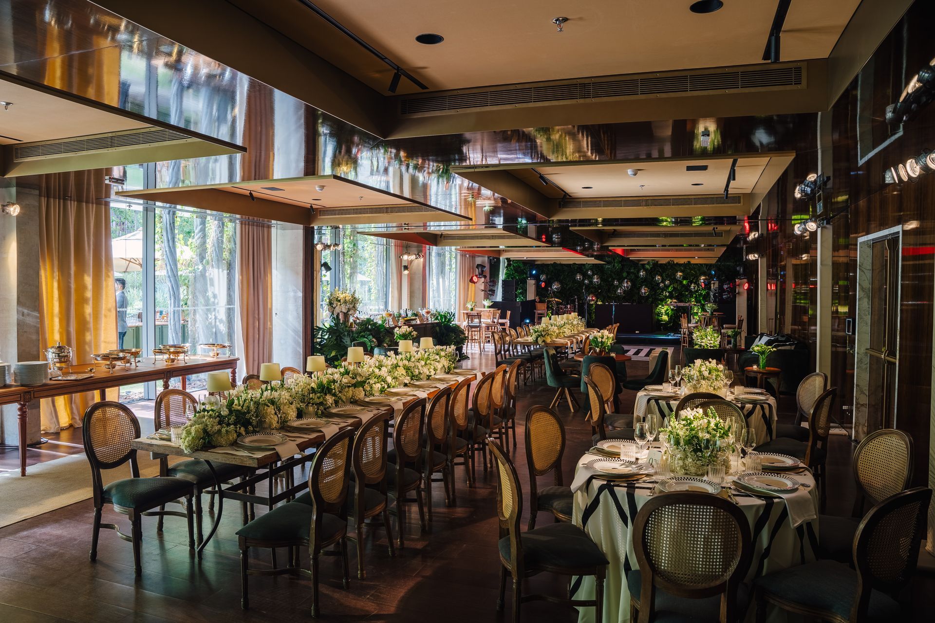 Uma grande sala de jantar com mesas e cadeiras preparada para uma recepção de casamento.