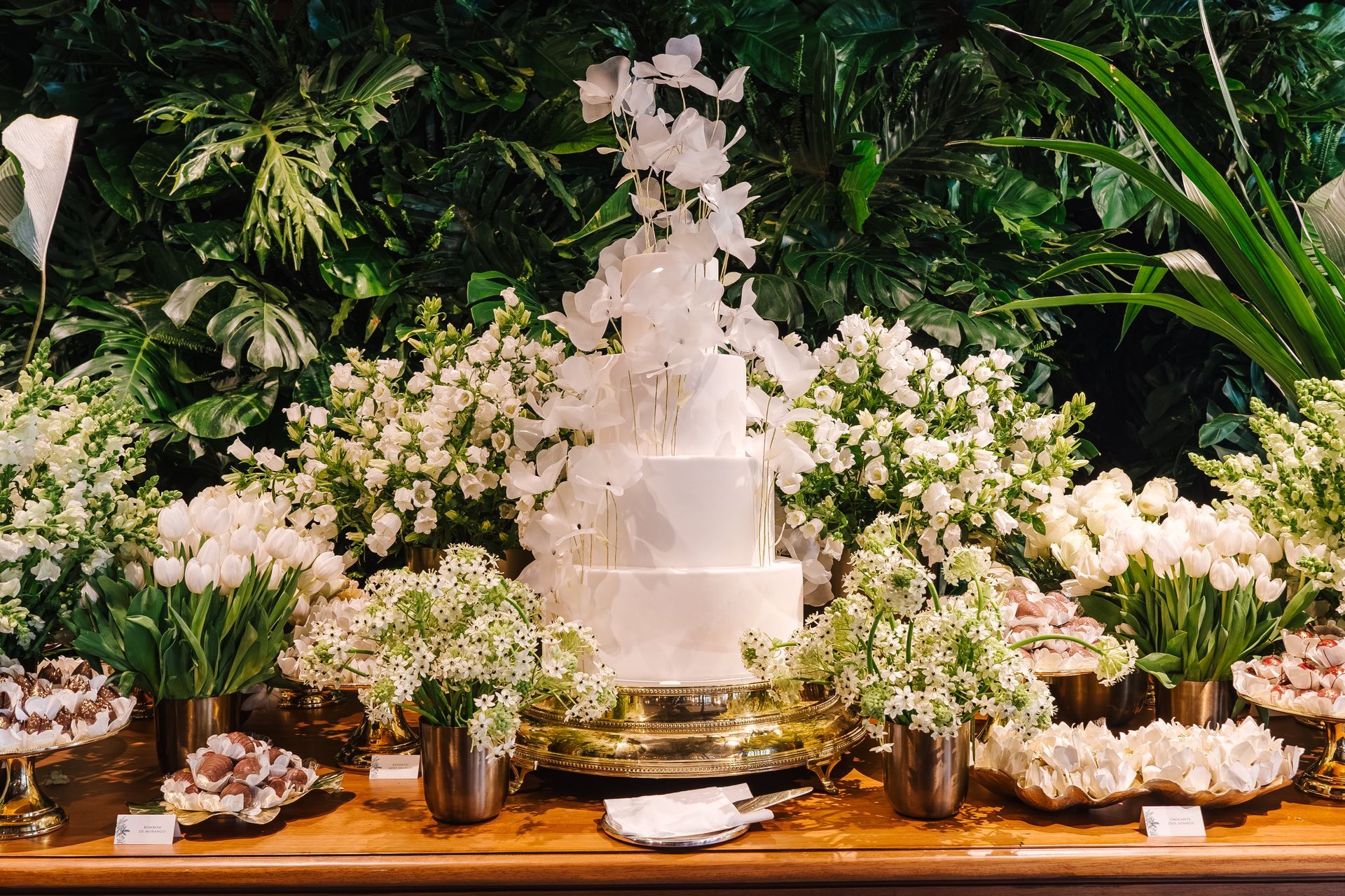 Um bolo de casamento está sobre uma mesa cercado por flores brancas.