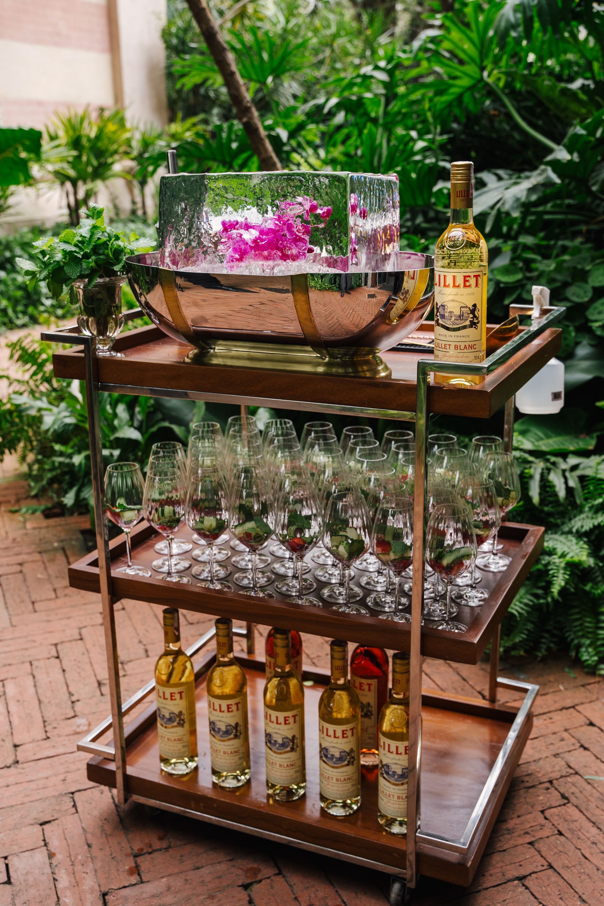 Um carrinho de bar cheio de garrafas de vinho e taças.