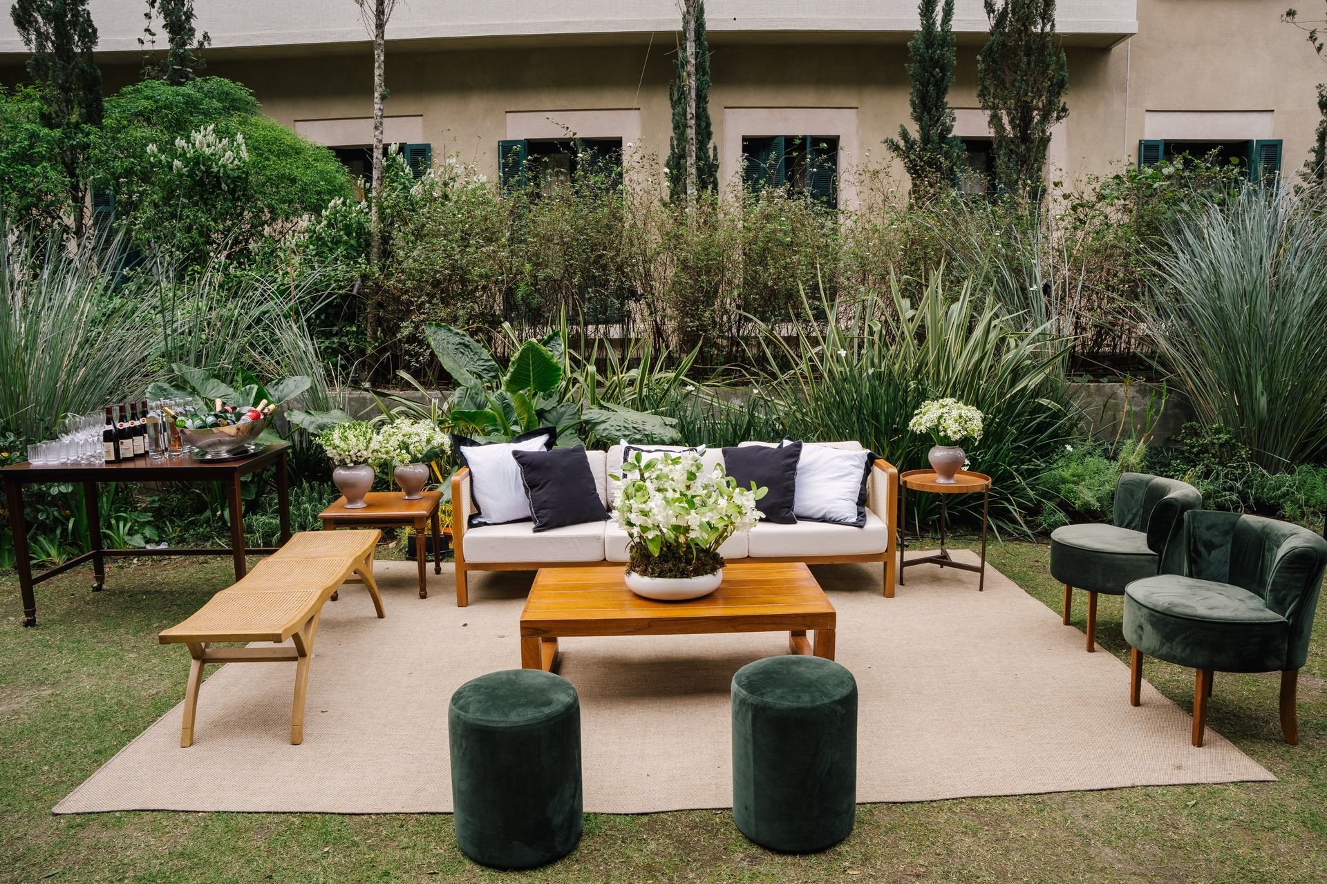 Um gramado com um sofá, cadeiras, mesa de centro e pufes.