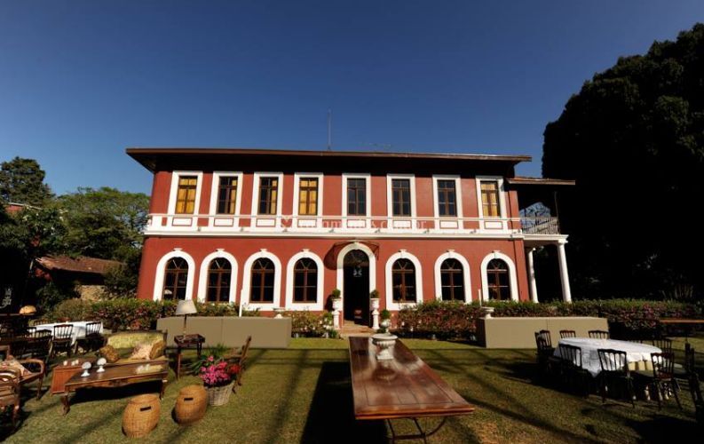Um grande prédio vermelho com muitas janelas e uma mesa na frente dele