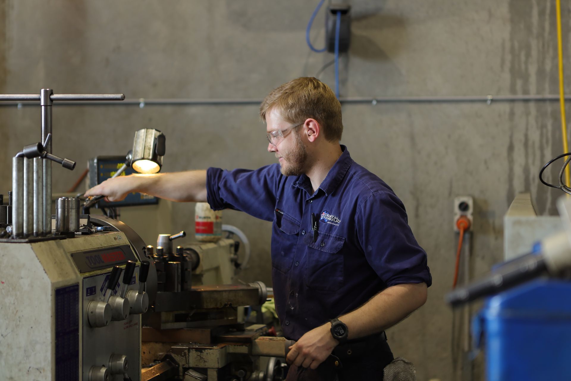 A Man Is Working On A Machine In A Factory — Coastal Hydraulics & Engineering Pty Ltd In Bungalow, QLD
