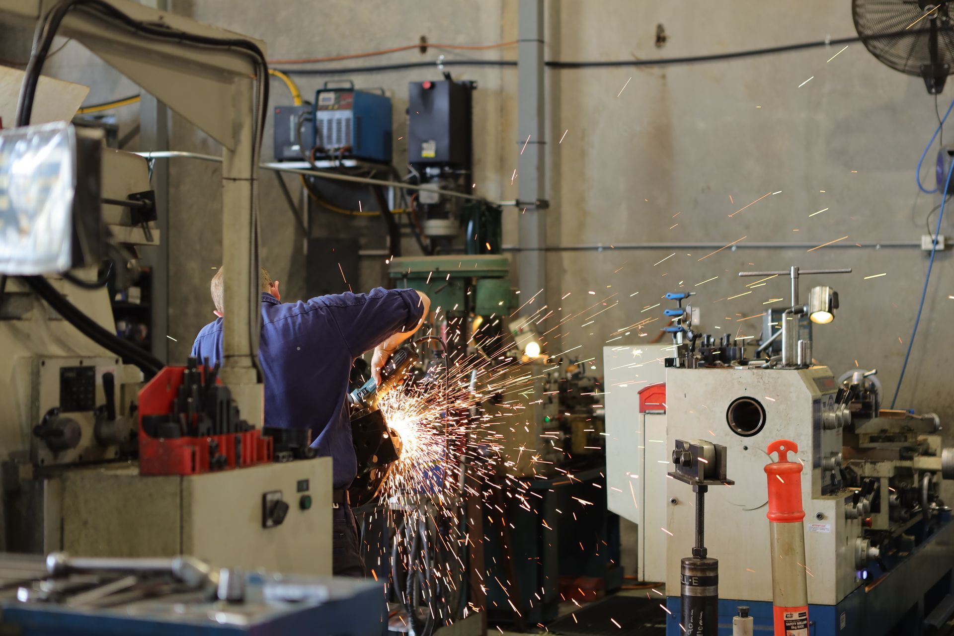 A Man Is Welding A Piece Of Metal In A Factory — Coastal Hydraulics & Engineering Pty Ltd In Mackay, QLD