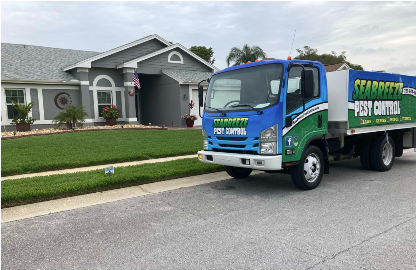 A blue and green truck is parked in front of a house.