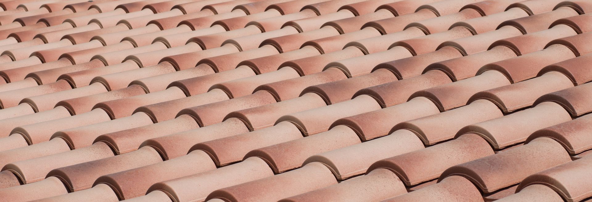 A pattern of overlapping, terracotta-colored clay roof tiles arranged in rows.