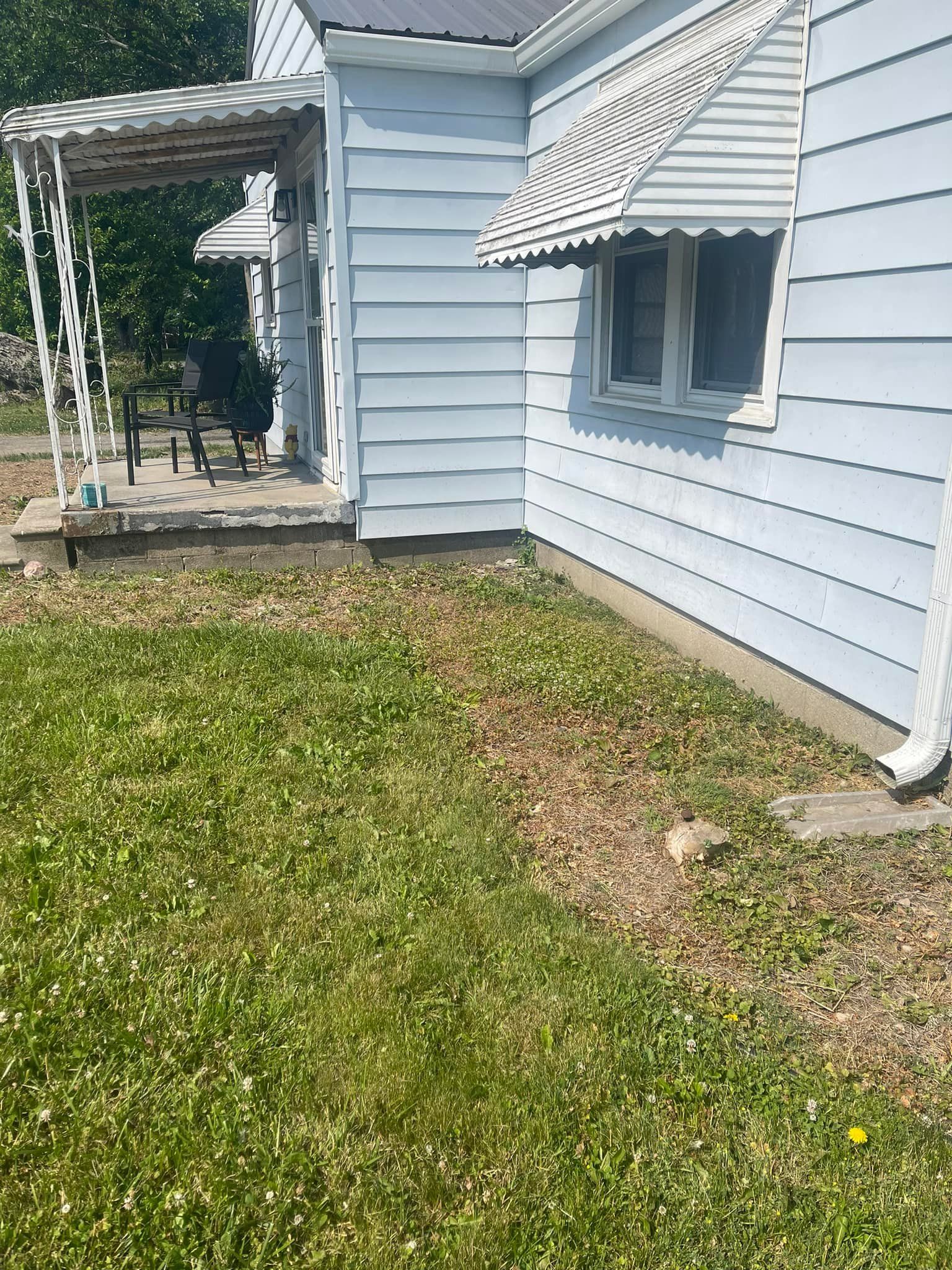 A blue house with a porch and a lawn in front of it.