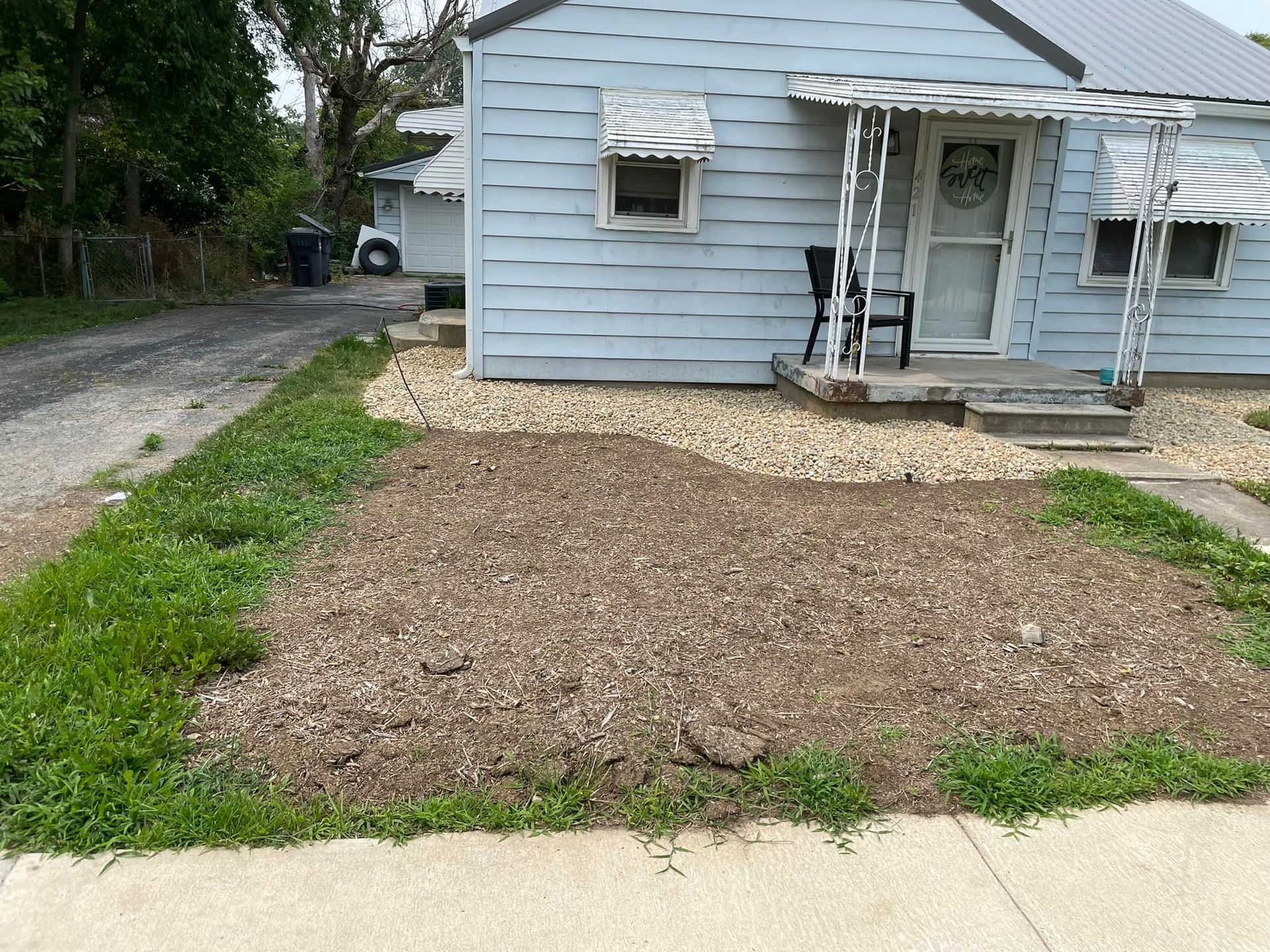 A small house with a covered porch and a lawn in front of it.