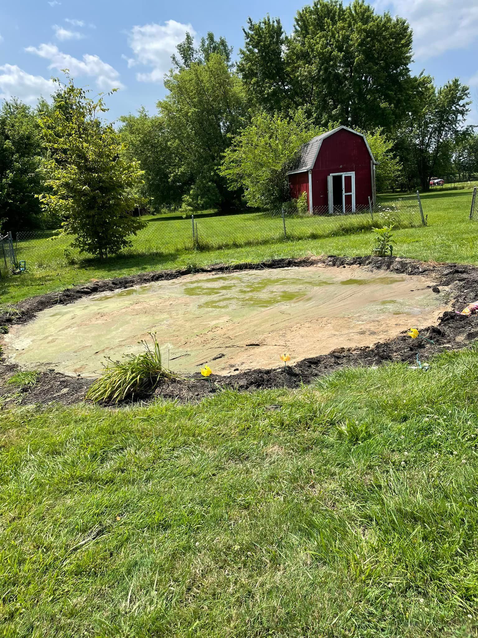 A red barn is sitting in the middle of a grassy field.