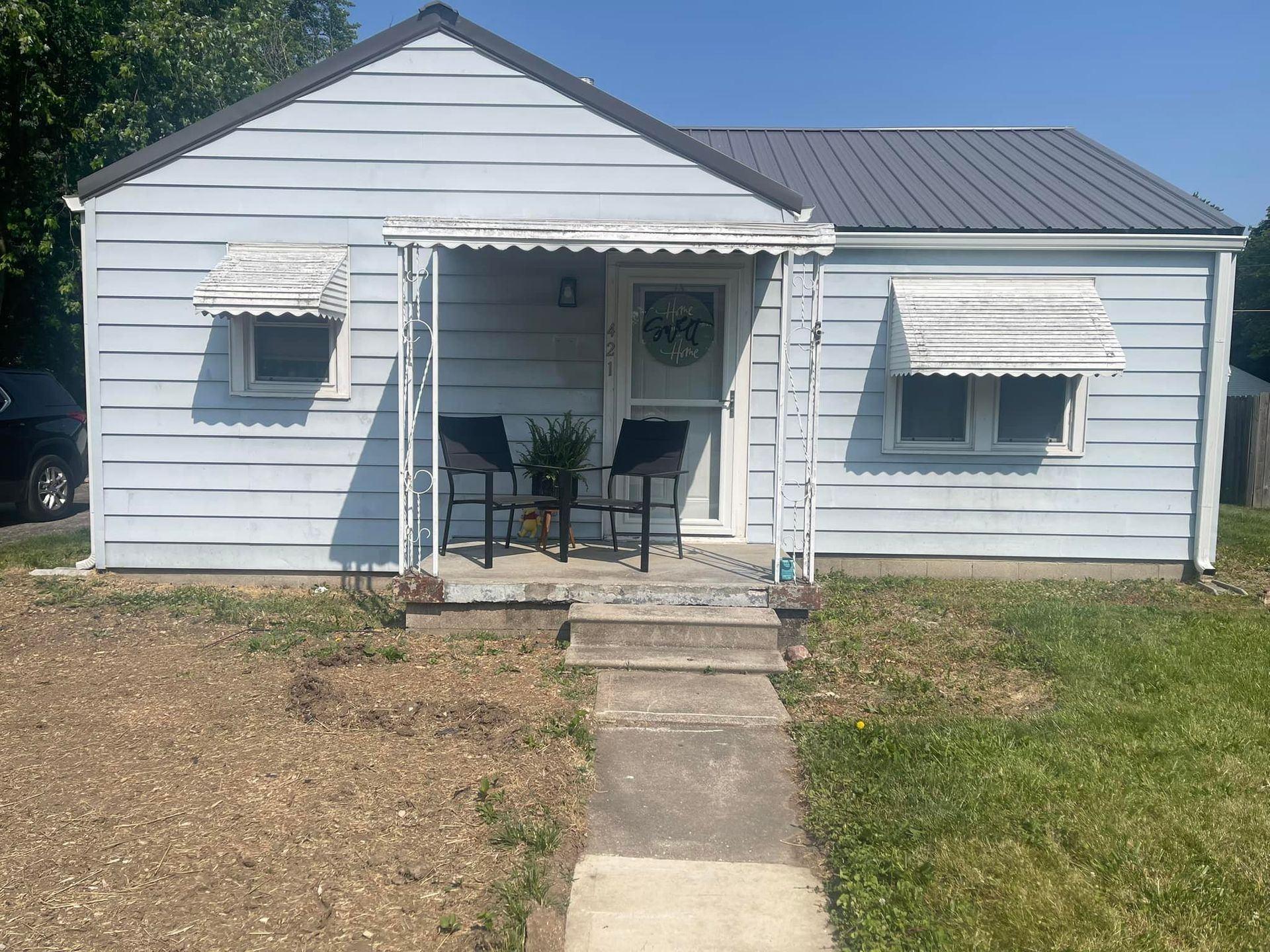 A small house with a porch and chairs in front of it.