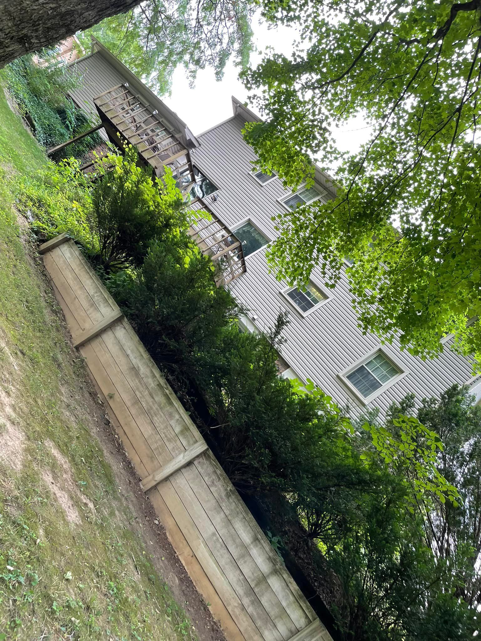 A house with a wooden fence in front of it surrounded by trees.