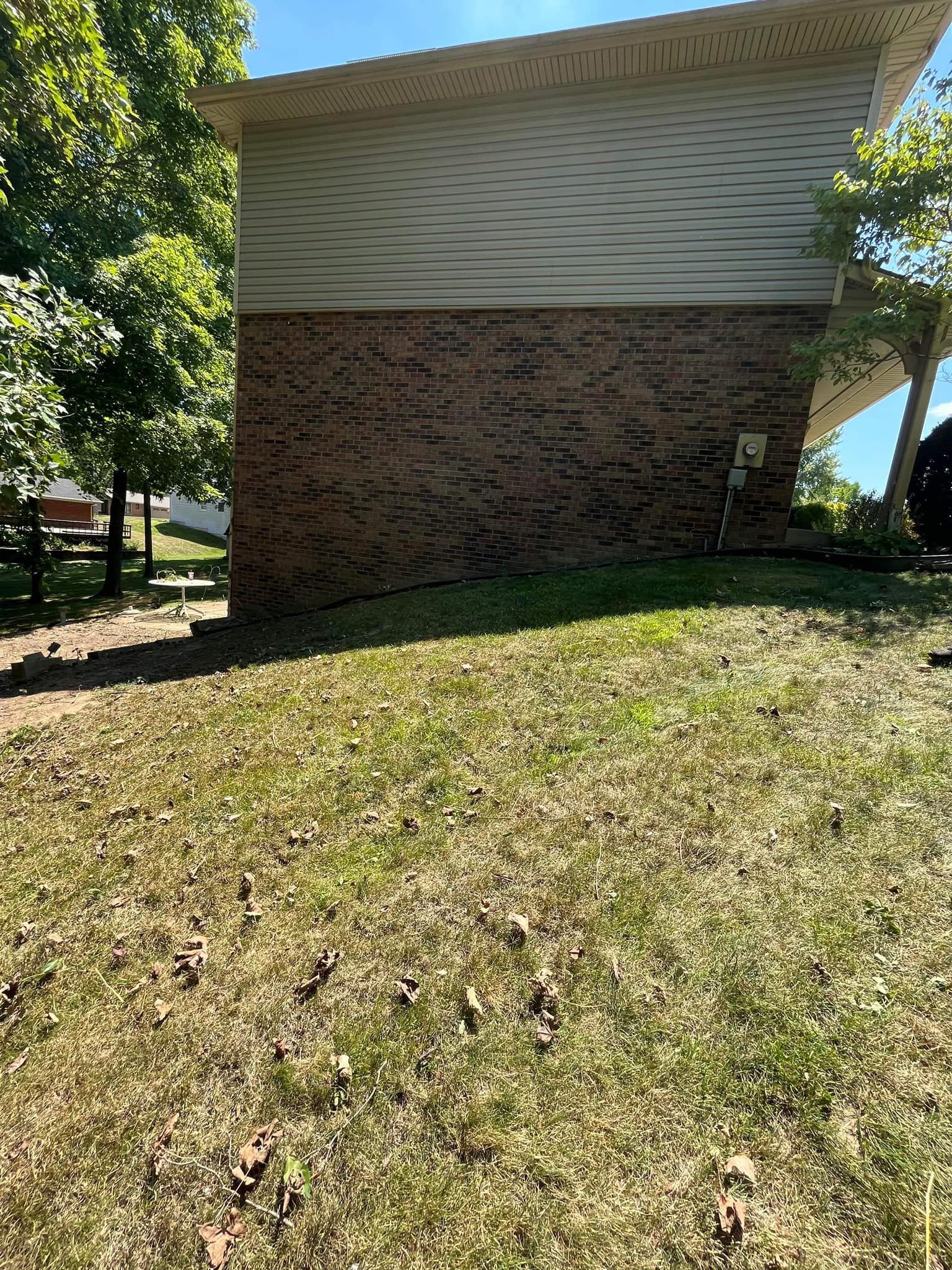 A brick house with a white siding and a large lawn in front of it.