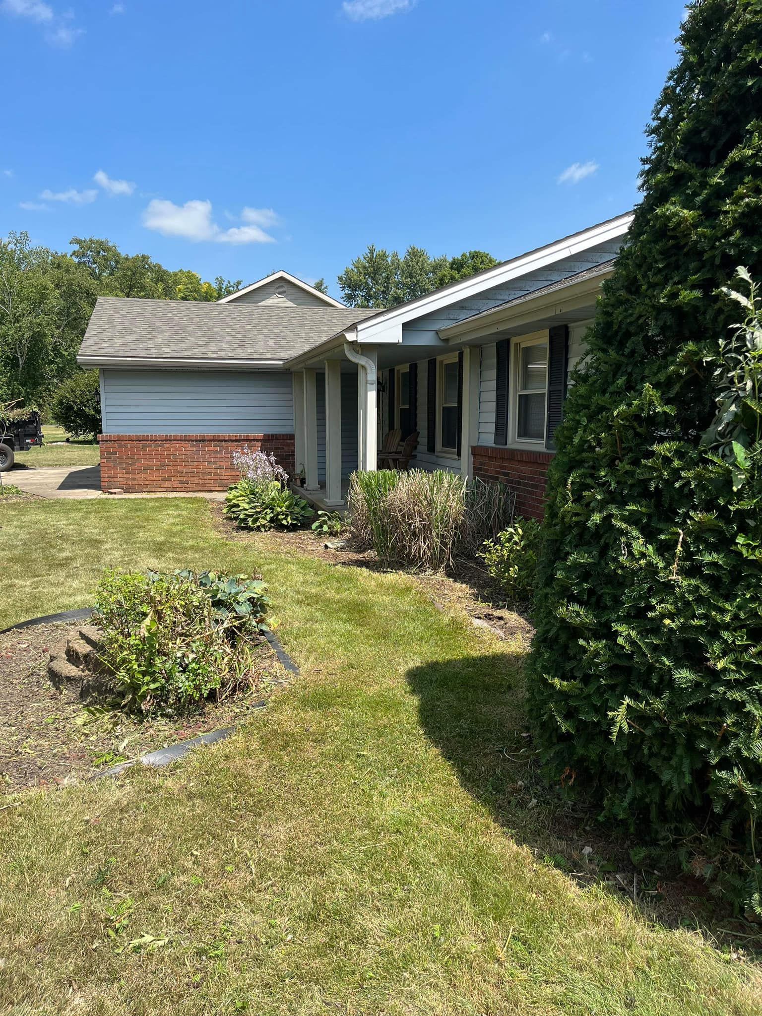 A house with a lush green lawn and trees in front of it on a sunny day.