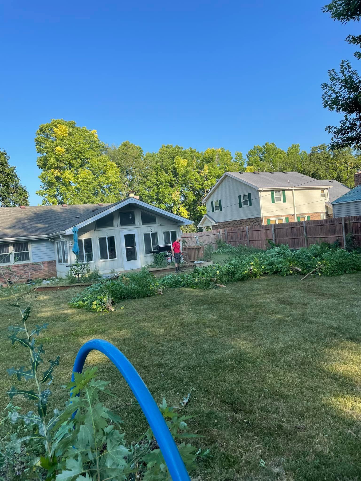 A blue hose is sitting in the grass in front of a house.