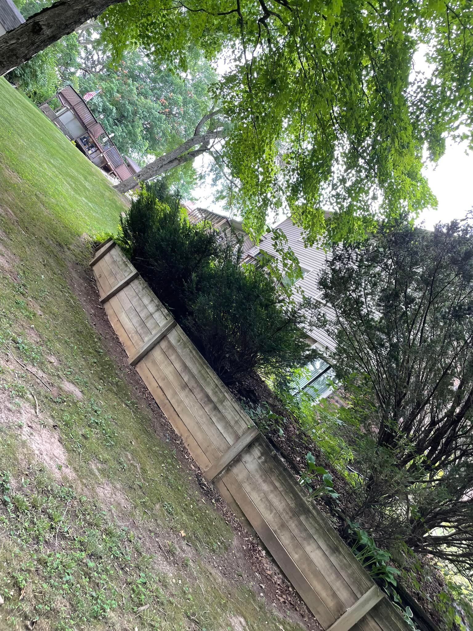 A wooden fence is surrounded by trees and grass in a yard.