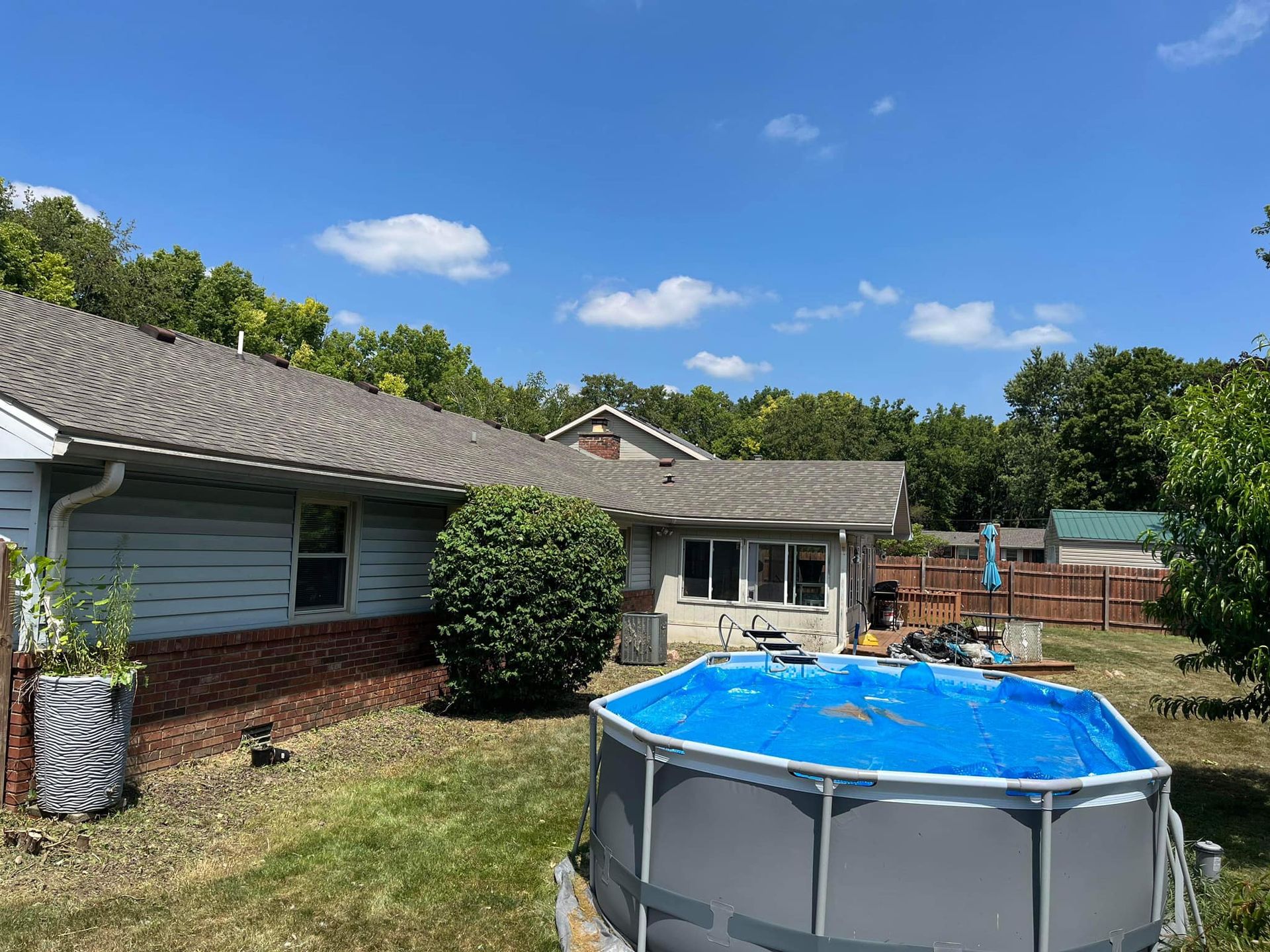 A large swimming pool is in the backyard of a house.