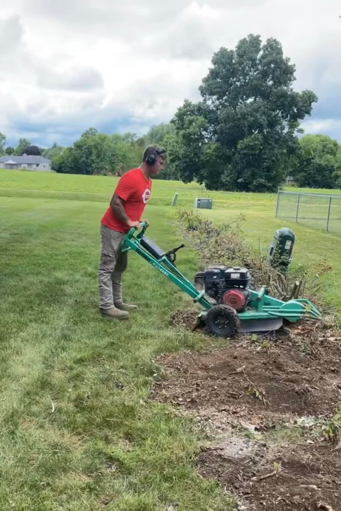 A man is using a stump grinder to remove a tree stump.