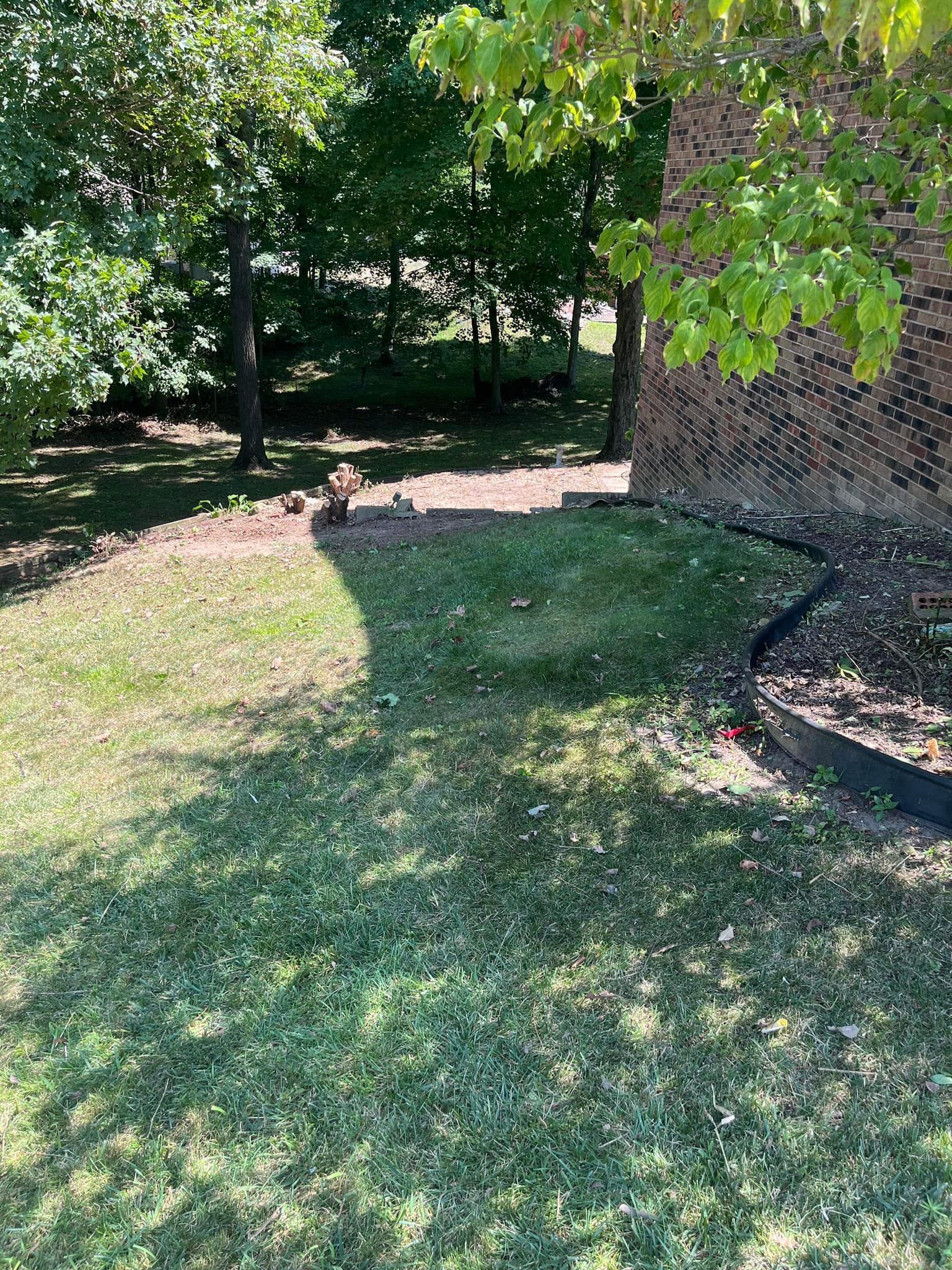 A lawn with a brick building in the background and trees in the background.