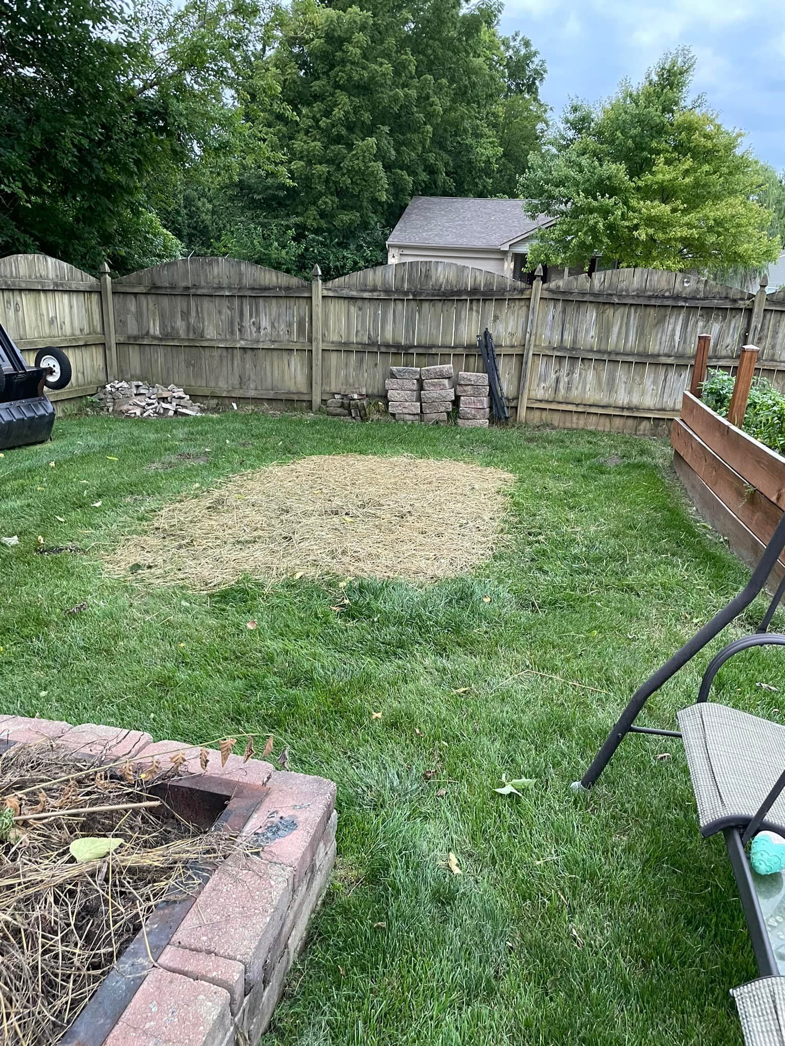 A backyard with a wooden fence and a fire pit.